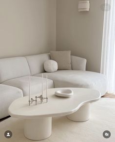 a living room with a white couch, table and candles on the coffee table in front of it