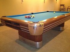 a pool table in a room with chairs and lights on the wall, along with two billiards