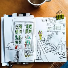 an open notebook with drawings on it next to a cup of coffee