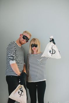 a man and woman are dressed up as money bags, one is holding a bag with an anchor on it