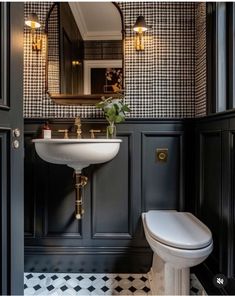 a white toilet sitting next to a sink in a bathroom under a mirror and lights