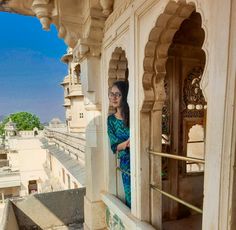 a woman standing on the balcony of a building