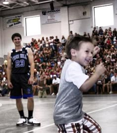 a young boy is playing with a frisbee in front of an audience at a basketball game