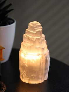 a lit candle sitting on top of a table next to a small potted plant