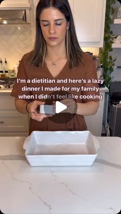 a woman standing in front of a white counter top holding a tray with food on it