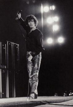 a black and white photo of a man on stage with his hands in the air