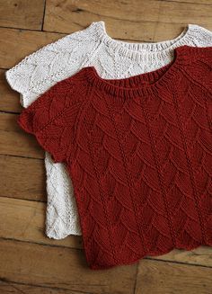 two red and white sweaters sitting on top of a wooden floor next to each other