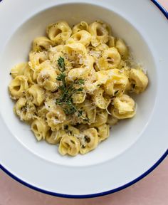 a white bowl filled with macaroni and cheese on top of a pink table