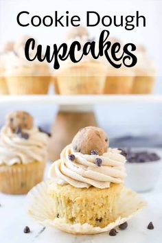 a cupcake with white frosting and chocolate chip cookies on top is shown in front of other cupcakes