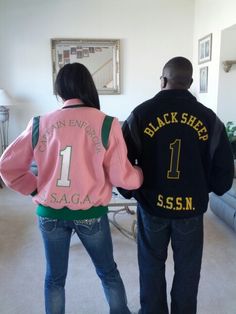 two people standing in a living room with jackets on their back and one person wearing jeans