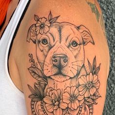 a woman's arm with a dog and flowers tattoo on the side of her shoulder