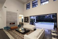 a living room with white furniture and large windows