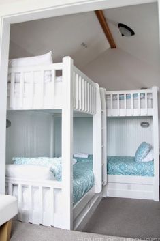 two bunk beds in a room with white walls and carpeted flooring, one is blue and the other is white