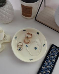 two wedding rings are sitting on a plate next to a cup and other items that have been placed around it