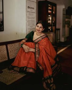 a woman in an orange sari sitting on a bench