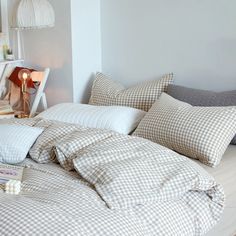 an unmade bed with white and brown checkered comforter on top of it