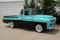 an old black and teal truck parked in front of a building