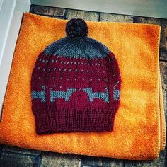 a knitted beanie sitting on top of an orange towel next to a door