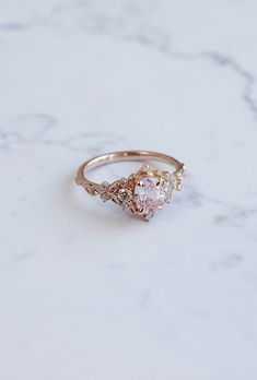 a close up of a ring on a white marble surface with an oval shaped diamond in the center