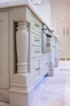 a large kitchen with white cabinets and marble flooring