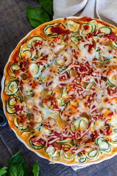 a pizza sitting on top of a white plate covered in cheese and veggies