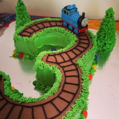 a thomas the train birthday cake with green frosting and trees on it's sides