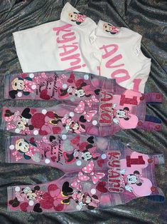 three minnie mouse onesuits are laying on a bed with pink and white shirts