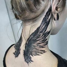 a woman's back neck with black wings on the upper part of her neck