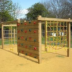 a wooden structure with climbing ropes on it in the sand at a play area for children