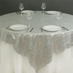 the table is set with silver sequins and place settings for four people to sit at