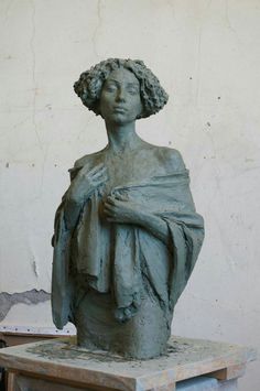 a statue of a woman with her arms folded over her chest, sitting on top of a table