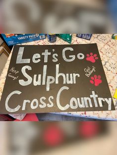 a sign that says let's go sulphur cross country with paw prints on it