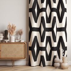 a black and white shower curtain next to a sideboard with vases on it