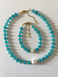 Enhance any ensemble with this exquisite necklace, adorned with faceted turquoise crystals, gold beads, and a pearled center. This elegant piece evokes a touch of Parisian chic with its timeless design. Step out in classic sophistication and timeless style with this luxurious and exclusive accessory. Size 15” long + 2” extension Bracelet 6'long +2" extension Handmade Necklace Tutorial, Parisian Blue, Turquoise Crystals, Parisienne Chic, Turquoise Crystal, Heart Hoop Earrings, Necklace And Bracelet, Black Necklace, Parisian Chic