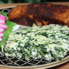 a close up of a plate of food with meat and spinach on it,