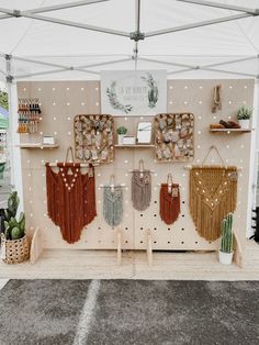 a booth with several handmade bags hanging on the wall and cactus plants in pots