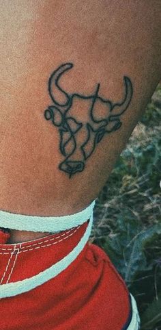 a tattoo on the back of a woman's leg with an arrow and bull head