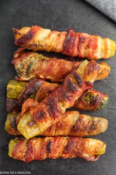 bacon wrapped jalapenos on a black plate with a gray napkin in the background