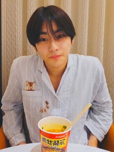 a woman sitting at a table with a bowl of soup in front of her and chopsticks