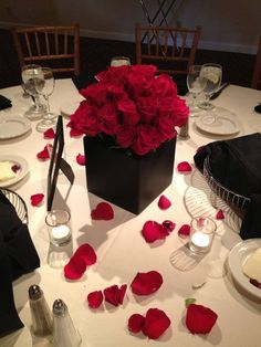 a white table topped with red roses and plates