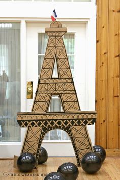 a cardboard model of the eiffel tower with bowling balls in front of it