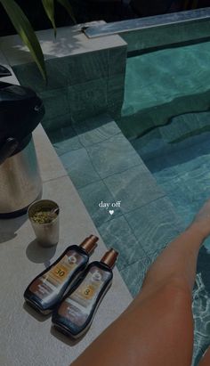 a woman's feet in the water next to two bottles of body lotion