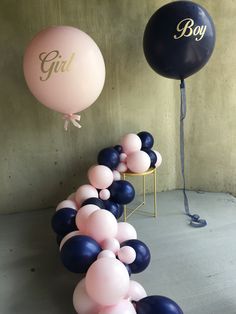 some balloons that are in the air and one is pink, blue and white with a monogrammed letter on it