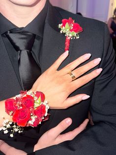 a man in a suit and tie holding a bouquet of red roses on his lapel