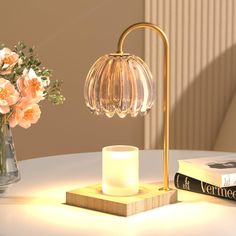 a table with a lamp, book and flowers on it