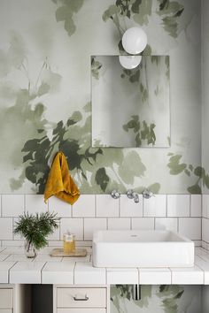 a white sink sitting under a mirror next to a wall mounted faucet in a bathroom