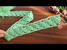 someone crocheting the edge of a piece of green yarn with a knitting needle