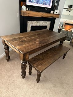 a wooden table with two benches in front of a fireplace