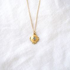 This small but mighty pendant is round with small granulation details on the top, bottom and sides, and bezel set with a teal Montana Sapphire. Product details: Pendant only or on 18" Oro chain Materials: 18k gold pendant Measurements: .5 inch x .5 inch Gold Birthstone Necklace With Bezel Setting Round Pendant, Recycled Gold Birthstone Pendant Necklace, Yellow Gold Pendant Charm Necklace With Satellite Chain, Tarnish Resistant Yellow Gold Birthstone Pendant Necklace, Gold Pendant Necklace With Bezel Setting, Yellow Gold Brass Necklace With Birthstone, Sapphire Necklace Pendants, Small But Mighty, Montana Sapphire