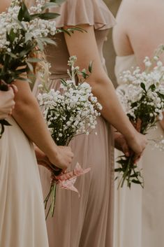 the bridesmaids are holding their bouquets with white flowers in each one's hands